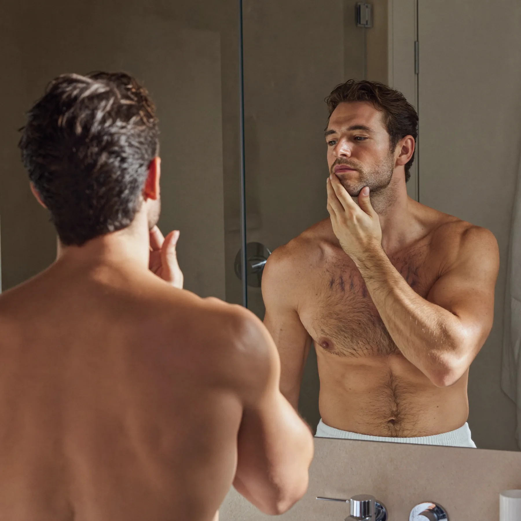 Mann beim Self-Care im Spiegel — Haarpflege als Routine
